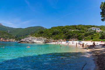 CORFU / GREECE - JUNE 22, 2019: People visit famous Rovinia beach with clear water in Corfu Island.