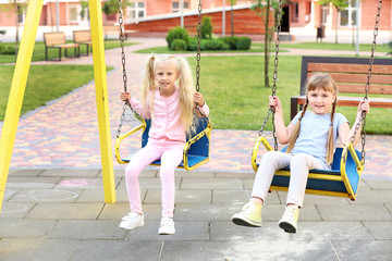 Cute little girls playing on swings in park