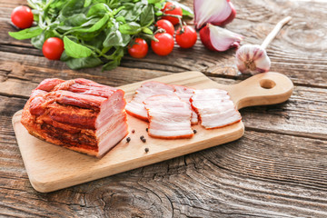 Board with tasty smoked meat on wooden table