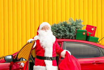 Santa Claus with gifts in bag getting out of car outdoors