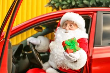 Santa Claus giving Christmas gift while sitting in car