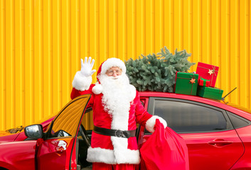 Santa Claus with gifts in bag near car outdoors