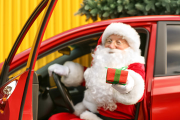 Santa Claus giving Christmas gift while sitting in car