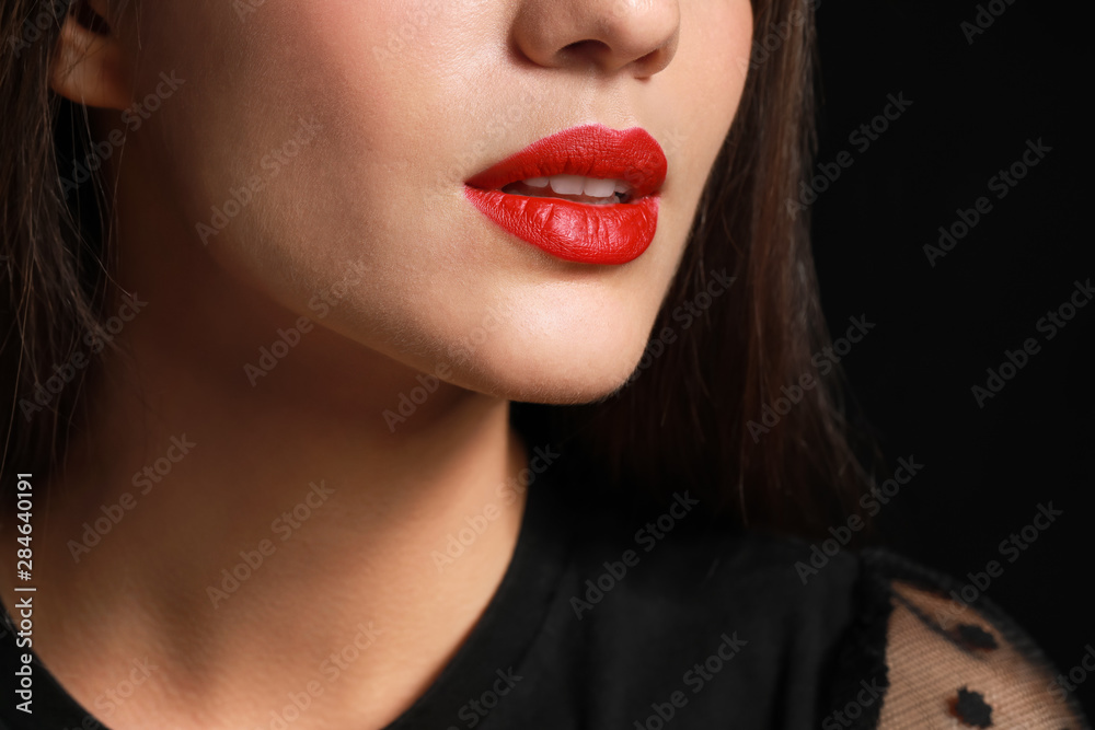 Sticker Beautiful young woman with bright lipstick on dark background, closeup