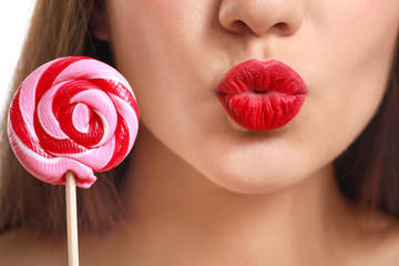 Beautiful young woman with bright lipstick and lollipop, closeup