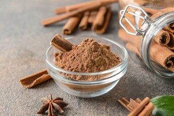Bowl with cinnamon powder on grey table
