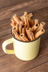 Mug with aromatic cinnamon sticks on wooden table