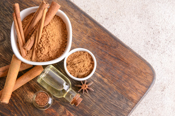 Aromatic cinnamon sticks, powder and essential oil on table
