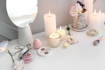 Beautiful burning candles and cosmetics on dressing table