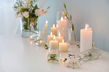 Beautiful burning candles and flowers on table