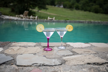Glass of martini cocktail at swimming pool with ocean and palm tree background. A glass of blue martini cocktail welcome drink bar.Selective focus. season and holidays concept.