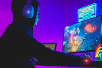 Young gamer playing at strategy online game - Male guy having fun gaming and streaming online - New technology game trends and entertainment concept - Focus on his hand