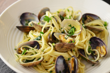 Pasta with mussels and basil on wooden table.