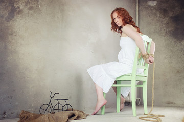 Young girl tied up on the floor. The abducted girl. The victim of violence sits on the floor with...