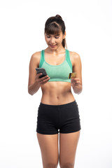 Fototapeta na wymiar Fitness woman using mobile phone and holding credit card isolate in white background. Asian girl, happy smile as purchase complete.