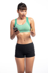 Fototapeta na wymiar Fitness woman using mobile phone and holding credit card isolate in white background. Asian girl, very shock look.