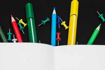 School concept - notepad, pencils, stationery buttons, felt-tip pens, isolated on black background © volodymyrv