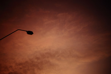 light pole silhouette and red hot sunset sky. rust Colour cloud background. industrial scene concept.