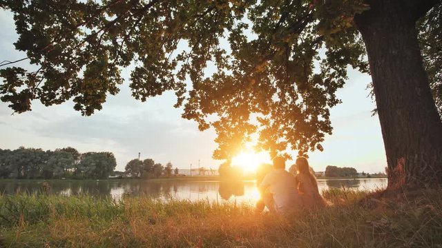 A young couple stands on a lake at sunset. Video on the move.