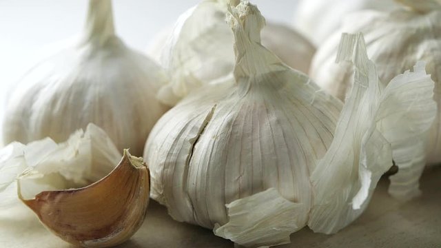 Whole garlic bulbs and garlic skin is blown away in slow motion