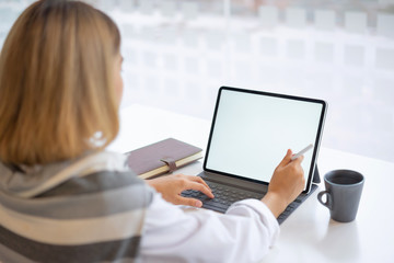 Business woman using and typing on mockup white screen laptop at her office.