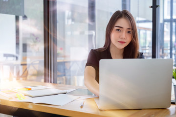 Attractive young asian freelancer business woman working with computer laptop in co-working space or coffee shop.