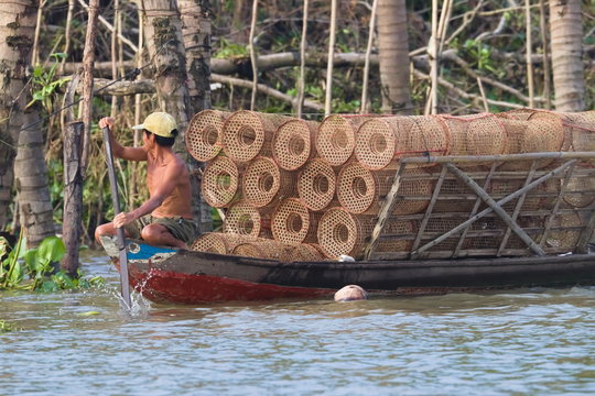 Fischer mit Reusen auf Holzboot am Rudern
