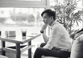 A young Asian businessman is waiting for a partner in a cafe. Business meeting in the restaurant. A Korean young man talking on the phone in a cafe.