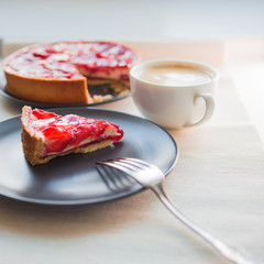 Still life with a Cup of coffee and sweet dessert with strawberries, cheesecake cake with slices of berries in jelly on top.