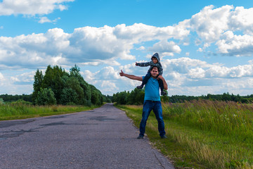 father and son hitchhiking along a road