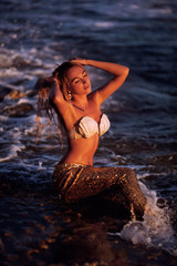 Fototapeta premium beautiful mermaid with golden tail sits on the seashore