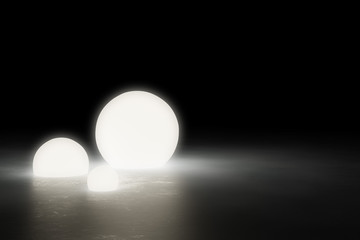 Three warm glowing sphere light objects on shiny modern industrial concrete floor in dark room with copy space - 3D illustratrion