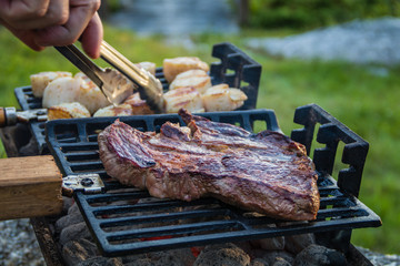 Steak and Scallops grilling on a hibachi as hot charcoal develops smoke and flames on a summer night