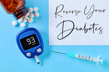 Reverse your diabetes concept. Close up top down view of glucose meter, drug pills, insulin syringe...