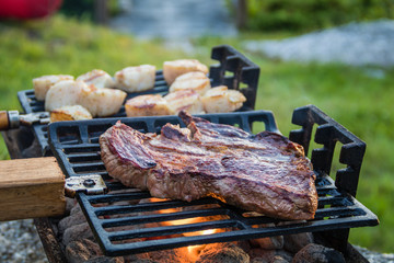 Steak and Scallops grilling on a hibachi as hot charcoal develops smoke and flames on a summer night