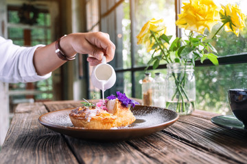 A woman pouring milk into a piece of coconut pie with a beautiful decoration in a plate