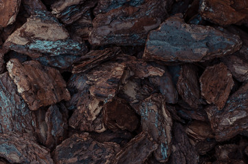Natural background of red and brown pieces of wood chips from pine bark for gardening or natural themes. Mulch for plants and flowers and for garden decor. Top view with copy space.