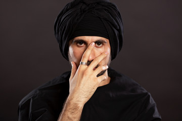 Young handsome man male in muslim turban. Close-up. Black background.