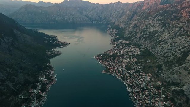 Overhead aerial view of rooftops and streets in historic old town of Kotor and Dobrota and bay for liner and boats in Montenegro in 4k