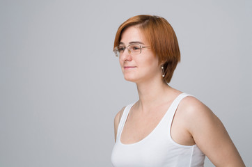 The light casual portrait of young woman with ginger hair and in glasses