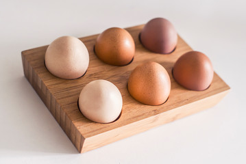 Wooden holder with chicken eggs on table