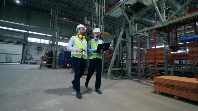 Factory interior and two male engineers walking across it