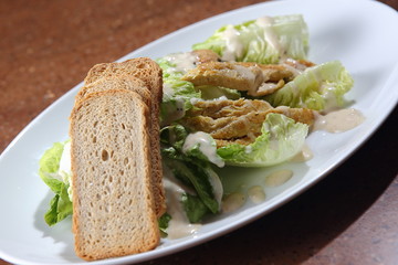 Caesar salad served with roast chicken, fresh lettuce, toasted garlic bread, Dijon mustard, Parmesan cheese and black pepper.