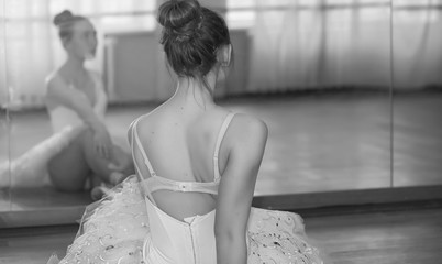 Young ballet dancer on a warm-up. The ballerina is preparing to perform in the studio. A girl in ballet clothes and shoes kneads by the handrails.