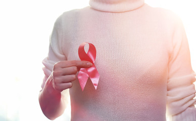 The red ribbon of the girl. The girl is holding a red ribbon. Health concept and red ribbon. Breast cancer.