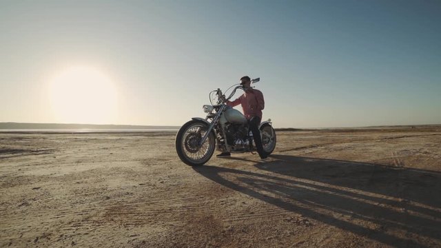 Motorcyclist driving his motorbike on the dirt road during sunset slow motion 