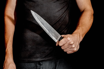 Man's hand holds a knife on black background. topics of violence and murder. thief, killer, rapist,...