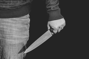 Man's hand holds a knife. topics of violence and murder. thief, killer, rapist, maniac. black and...