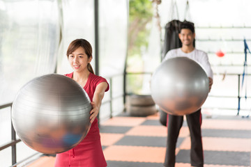 Asian men and women are exercising with the ball in the gym.