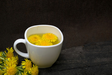 Dandelion flower tea infusion in white cup close up